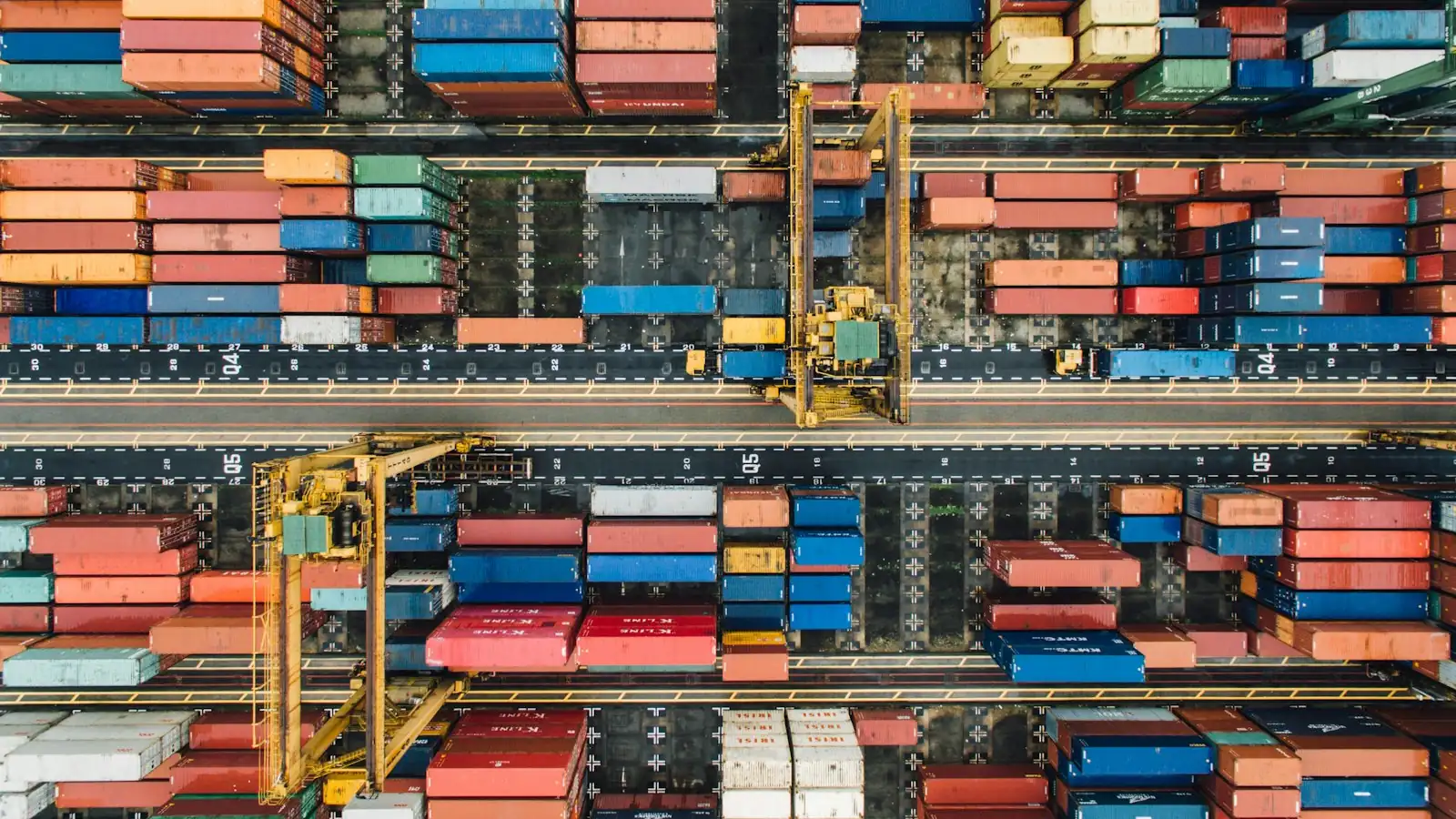 Aerial view of a container port with stacked containers and cranes